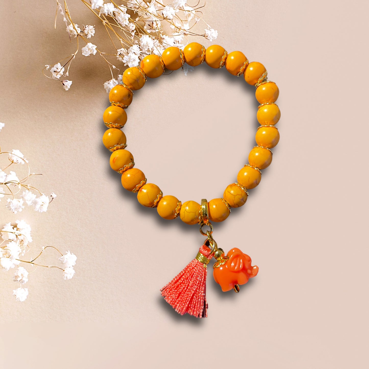 Armband YARA aus orangenen Perlen mit einem Anhänger Elefant und kleiner Quaste