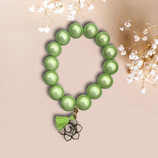 Armband WANIDA aus leuchenden Miracle Perlen in grün mit einem Anhänger OM Blume und einer Quaste