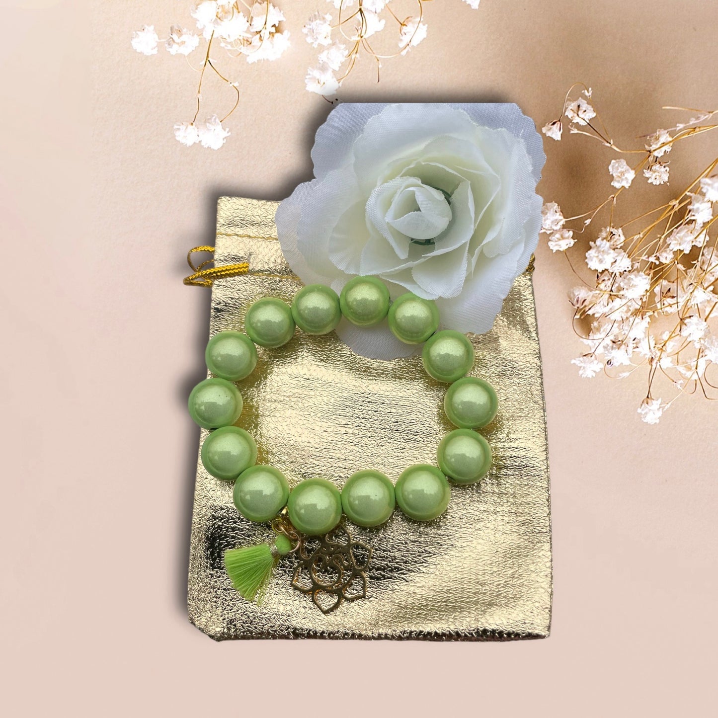 Armband WANIDA aus leuchenden Miracle Perlen in grün mit einem Anhänger OM Blume und einer Quaste