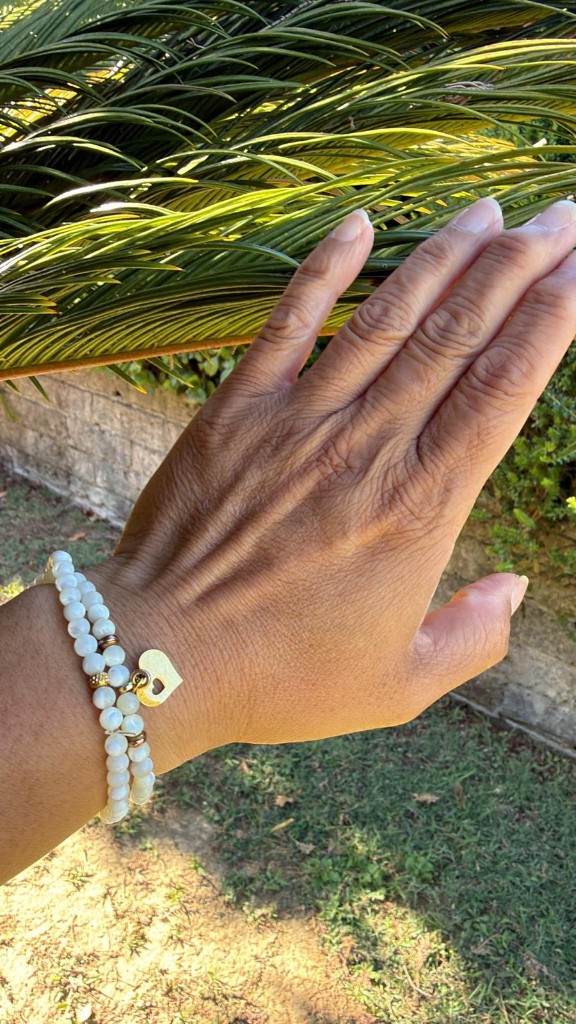 Perlenarmband mit Herz-Anhänger an der Hand